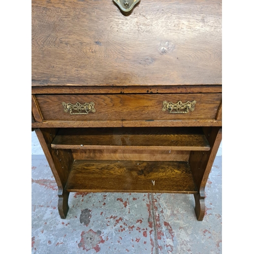 365 - An early 20th century oak bureau with fretwork galleried top, fall front, single drawer and two lowe... 