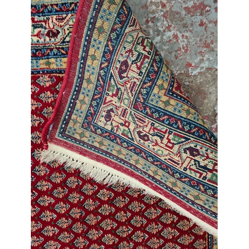 369 - A Persian style red tasselled rug - approx. 165cm x 95cm