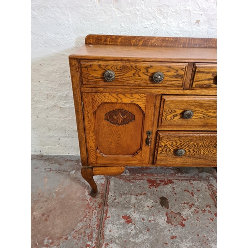 411 - An oak sideboard with two short drawers, two long drawers, carved panel cupboard door and cabriole s... 