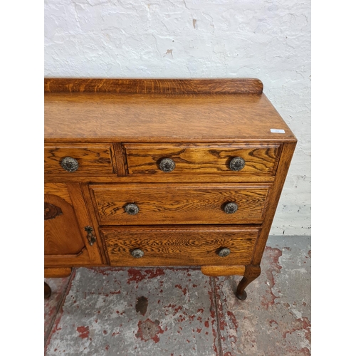 411 - An oak sideboard with two short drawers, two long drawers, carved panel cupboard door and cabriole s... 