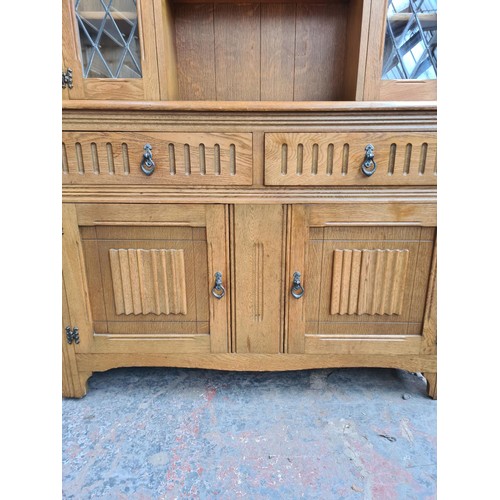 293 - An Agincourt oak dresser with two upper leaded glass doors, two drawers and two lower cupboard doors... 