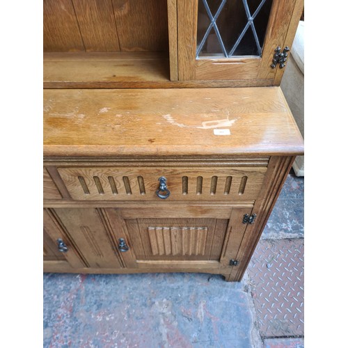 293 - An Agincourt oak dresser with two upper leaded glass doors, two drawers and two lower cupboard doors... 