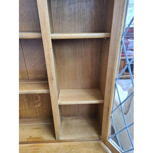 293 - An Agincourt oak dresser with two upper leaded glass doors, two drawers and two lower cupboard doors... 