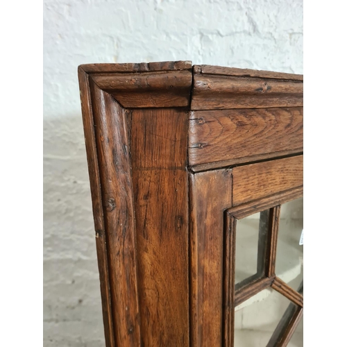 427 - A George III oak astral glazed wall mountable corner cabinet - approx. 99cm high x 64cm wide x 37cm ... 