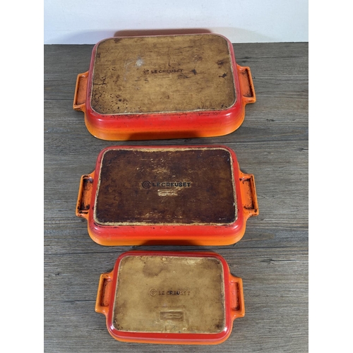 93 - Three Le Creuset orange glazed ceramic baking dishes