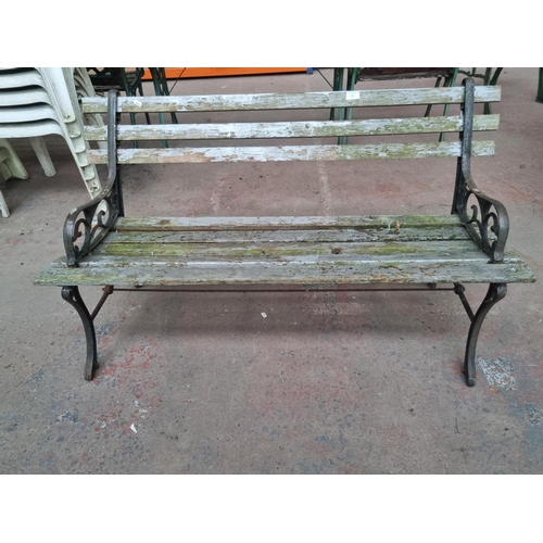 765 - A cast iron and wooden slatted two seater garden bench - approx. 74cm high x 123cm wide x 50cm deep