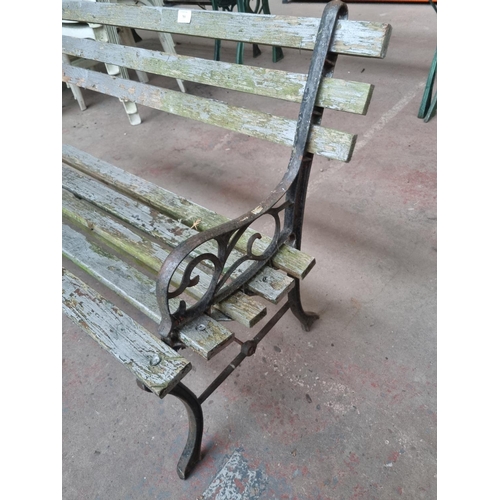 765 - A cast iron and wooden slatted two seater garden bench - approx. 74cm high x 123cm wide x 50cm deep