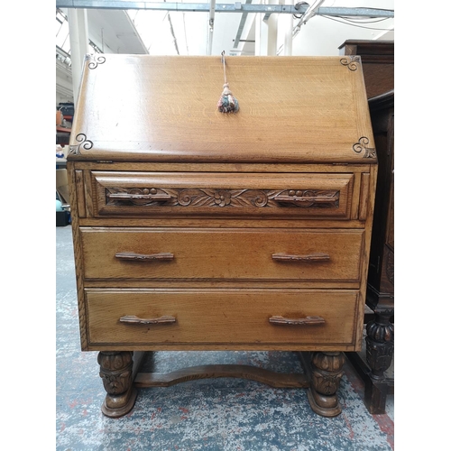 351 - A mid 20th century carved oak bureau with three drawers, fall front and baluster supports - approx. ... 