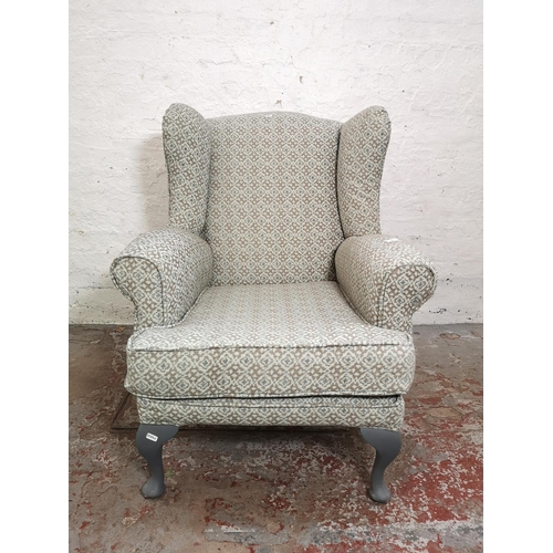 391 - A mid 20th century floral upholstered wingback armchair with grey painted cabriole supports - approx... 