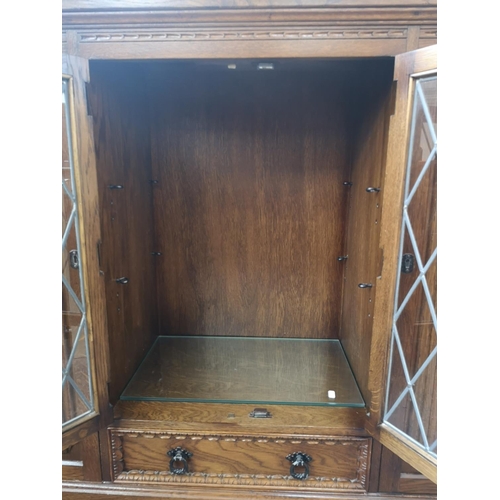 393 - An oak linenfold bookcase with two outer cupboard doors, two central leaded glass doors and single l... 