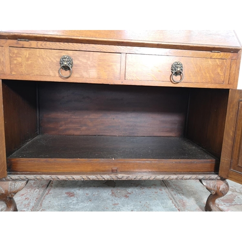 401 - An early/mid 20th century oak bureau with two drawers, two cupboard doors, fall front, ball and claw... 