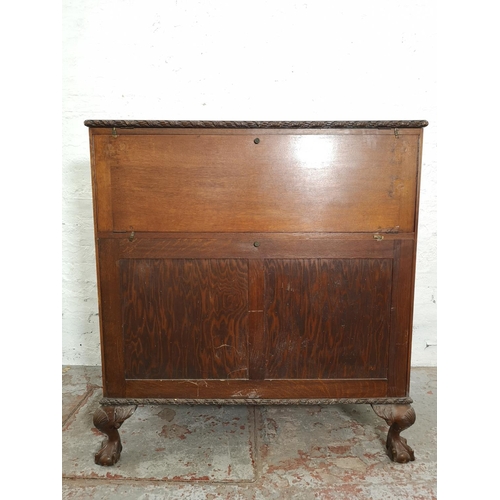 401 - An early/mid 20th century oak bureau with two drawers, two cupboard doors, fall front, ball and claw... 