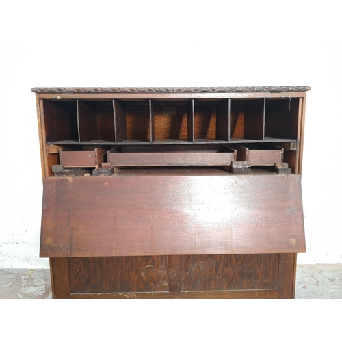 401 - An early/mid 20th century oak bureau with two drawers, two cupboard doors, fall front, ball and claw... 