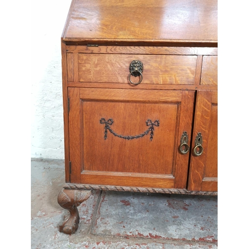 401 - An early/mid 20th century oak bureau with two drawers, two cupboard doors, fall front, ball and claw... 