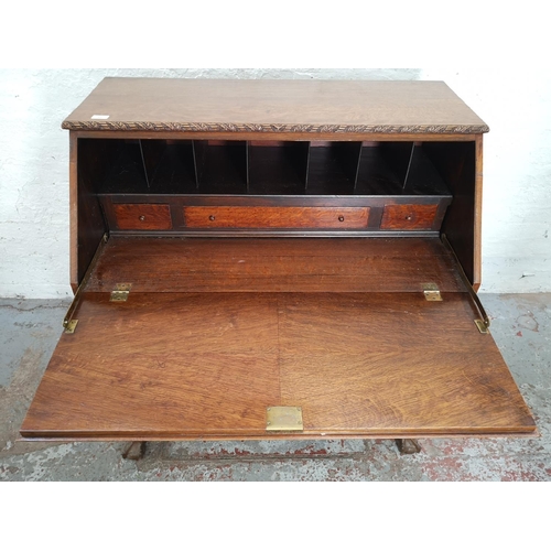 401 - An early/mid 20th century oak bureau with two drawers, two cupboard doors, fall front, ball and claw... 