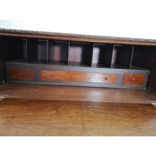 401 - An early/mid 20th century oak bureau with two drawers, two cupboard doors, fall front, ball and claw... 