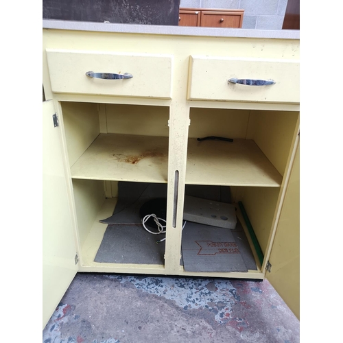 465 - A mid 20th century yellow painted and laminate kitchen cabinet with two drawers and two cupboard doo... 