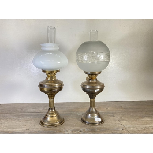 310 - A pair of brass oil lamps, one with milk glass shade and one with etched glass shade - approx. 54cm ... 