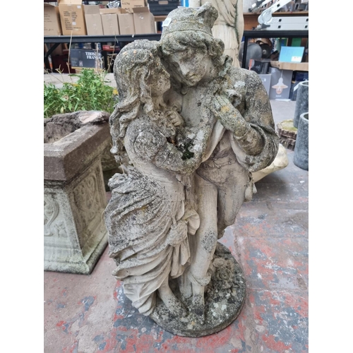 659 - A cast stone garden statue of a couple - approx. 77cm high