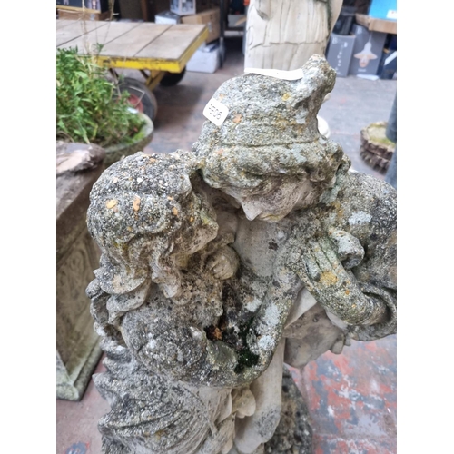 659 - A cast stone garden statue of a couple - approx. 77cm high