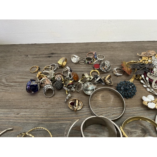 166C - A collection of assorted costume jewellery to include dress rings, brooches etc.