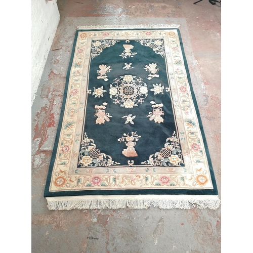 239 - An Oriental green and cream floral patterned rug - approx. 240cm x 155cm