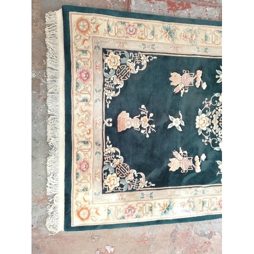 239 - An Oriental green and cream floral patterned rug - approx. 240cm x 155cm