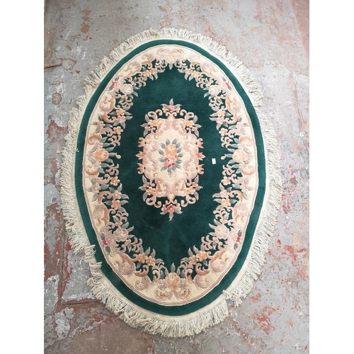 239A - A green and cream floral patterned oval rug - approx. 186cm x 125cm