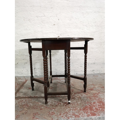 255 - A mid 20th century oak drop leaf occasional table with bobbin turned supports