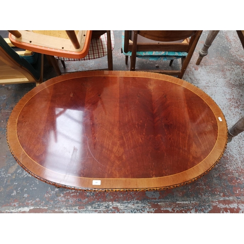 309 - A late 20th century yew wood effect oval twin pedestal coffee table with brass lion paw supports