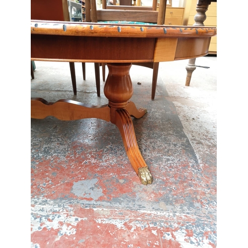 309 - A late 20th century yew wood effect oval twin pedestal coffee table with brass lion paw supports