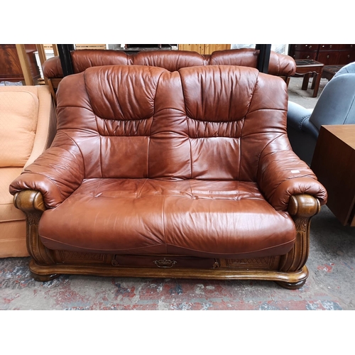 365 - A brown leather and carved oak three piece lounge suite comprising two two seater sofas and one thre... 