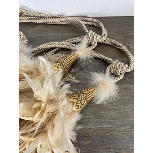 120 - Two pairs of gilded feather and tassel curtain tie backs