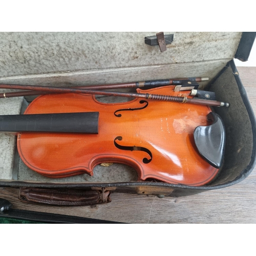 Two cased violins, one with three bows, fine tuners and spare tuning pegs