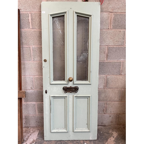 1007 - A green painted pine door with brass letterbox and handle - approx. 201cm high x 81cm wide