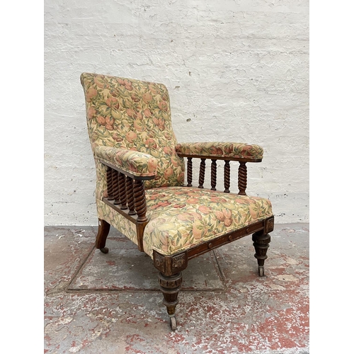 1010 - An early 20th century oak and floral upholstered armchair with barley twist design and brass castors... 