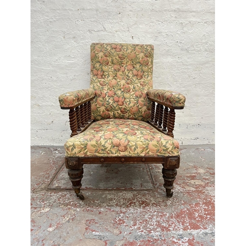 1010 - An early 20th century oak and floral upholstered armchair with barley twist design and brass castors... 