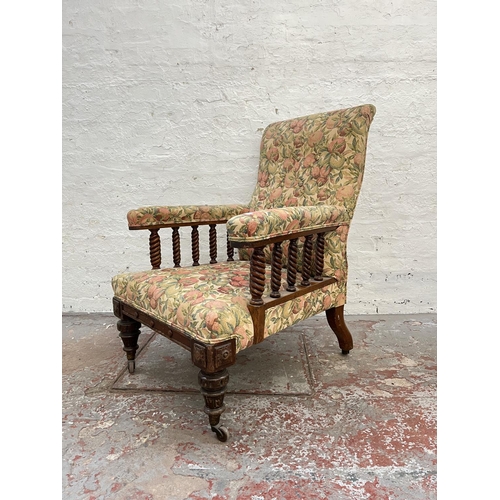 1010 - An early 20th century oak and floral upholstered armchair with barley twist design and brass castors... 