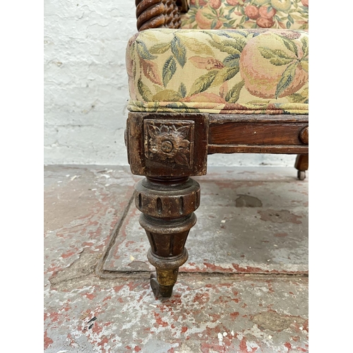 1010 - An early 20th century oak and floral upholstered armchair with barley twist design and brass castors... 