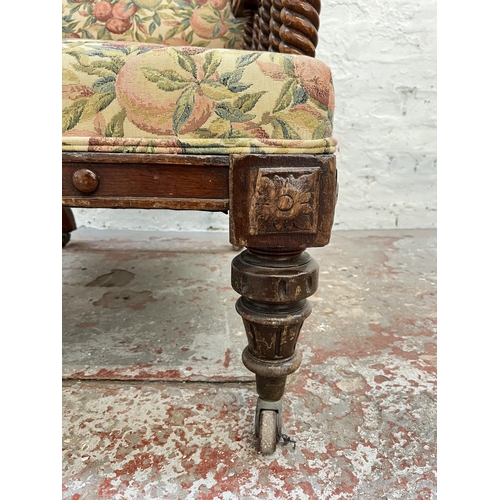 1010 - An early 20th century oak and floral upholstered armchair with barley twist design and brass castors... 