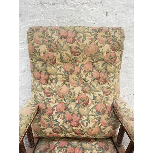 1010 - An early 20th century oak and floral upholstered armchair with barley twist design and brass castors... 