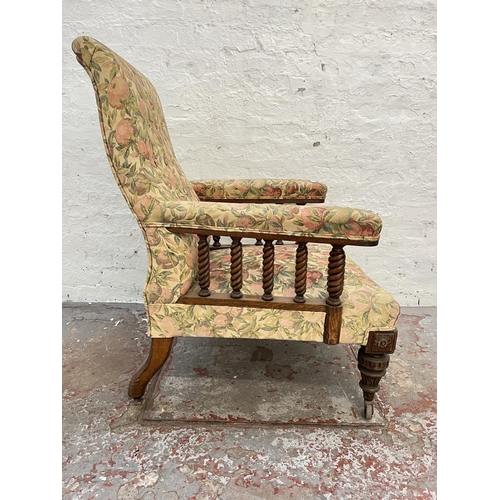 1010 - An early 20th century oak and floral upholstered armchair with barley twist design and brass castors... 