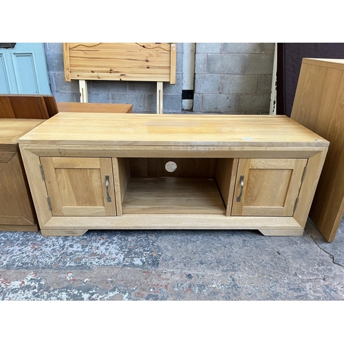 1016 - A modern oak TV stand with two cupboard doors - approx. 48cm high x 124cm wide x 45cm deep