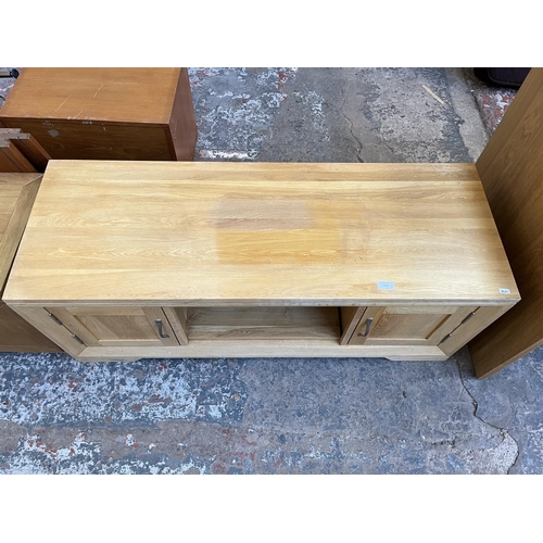 1016 - A modern oak TV stand with two cupboard doors - approx. 48cm high x 124cm wide x 45cm deep