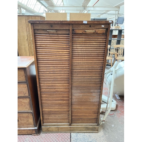 1031 - An early 20th century oak double tambour door cabinet - approx. 152cm high x 87cm wide x 37cm deep