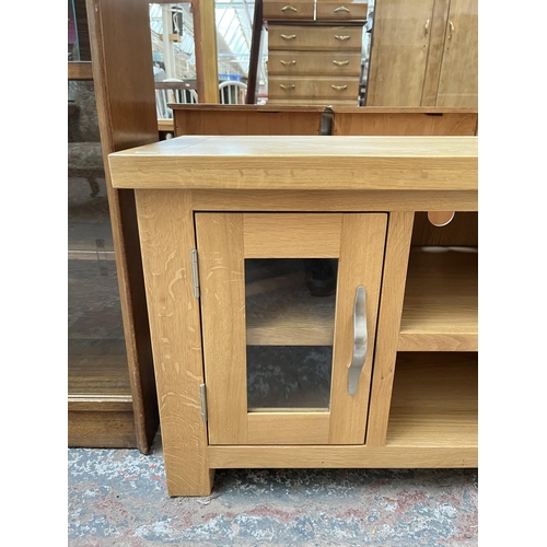 1033 - A modern oak TV stand with two glazed doors - approx. 56cm high x 115cm wide 44cm deep