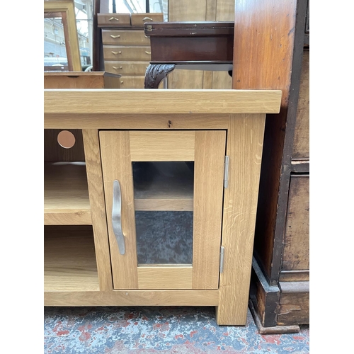 1033 - A modern oak TV stand with two glazed doors - approx. 56cm high x 115cm wide 44cm deep