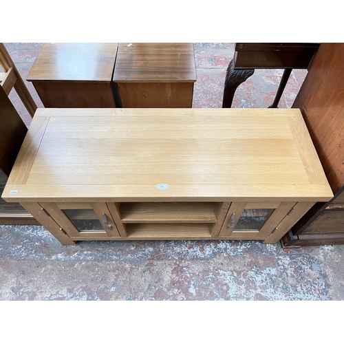 1033 - A modern oak TV stand with two glazed doors - approx. 56cm high x 115cm wide 44cm deep