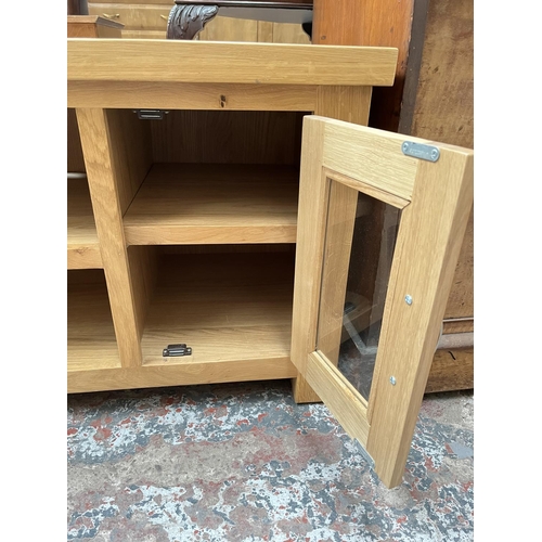 1033 - A modern oak TV stand with two glazed doors - approx. 56cm high x 115cm wide 44cm deep