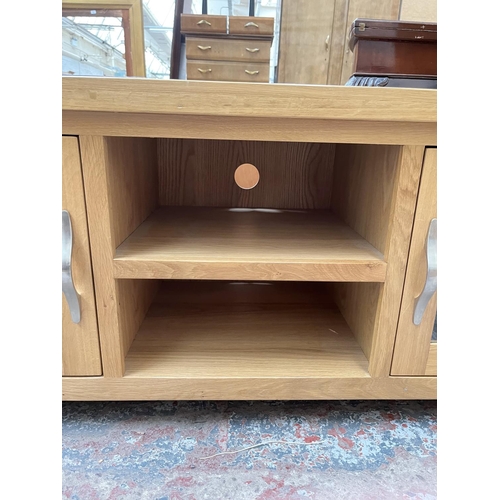 1033 - A modern oak TV stand with two glazed doors - approx. 56cm high x 115cm wide 44cm deep